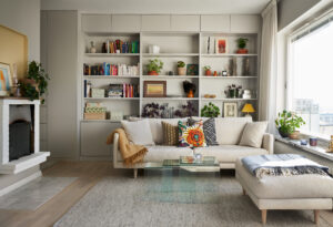 Vardagsrum med en beige soffa stående framför en platsbyggd bokhylla.